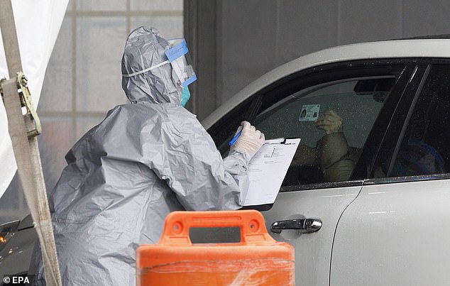 A medical professional is seen taking information from a person's ID at the testing center in New Rochelle on Friday